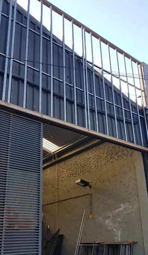 Fachada de um galpão no Jardim Canadá durante a obra: a estrutura de perfis de aço do light steel frame montada por cima da porta, ainda sem placas