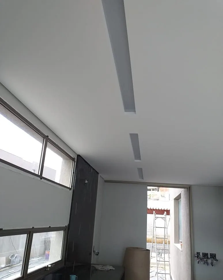 Casa na Península dos Pássaros, em Alphaville: ambiente com janelas altas e forro de gesso branco com rasgos lineares embutidos em linha no teto