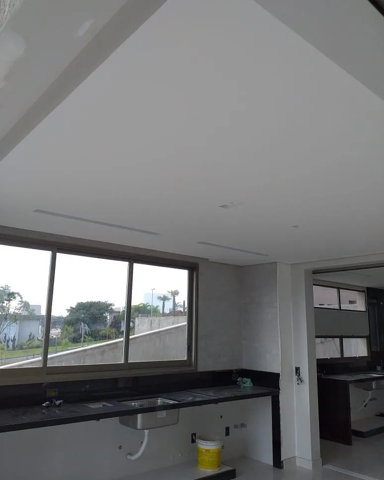 Casa na Península dos Pássaros, em Alphaville: cozinha com bancada de granito preto, janela para o jardim e forro de gesso liso com duas fendas lineares