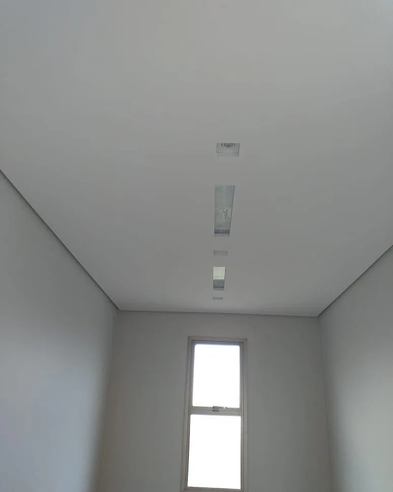 Casa na Península dos Pássaros, em Alphaville: quarto com janela estreita e forro de gesso com uma luminária linear embutida no centro do teto
