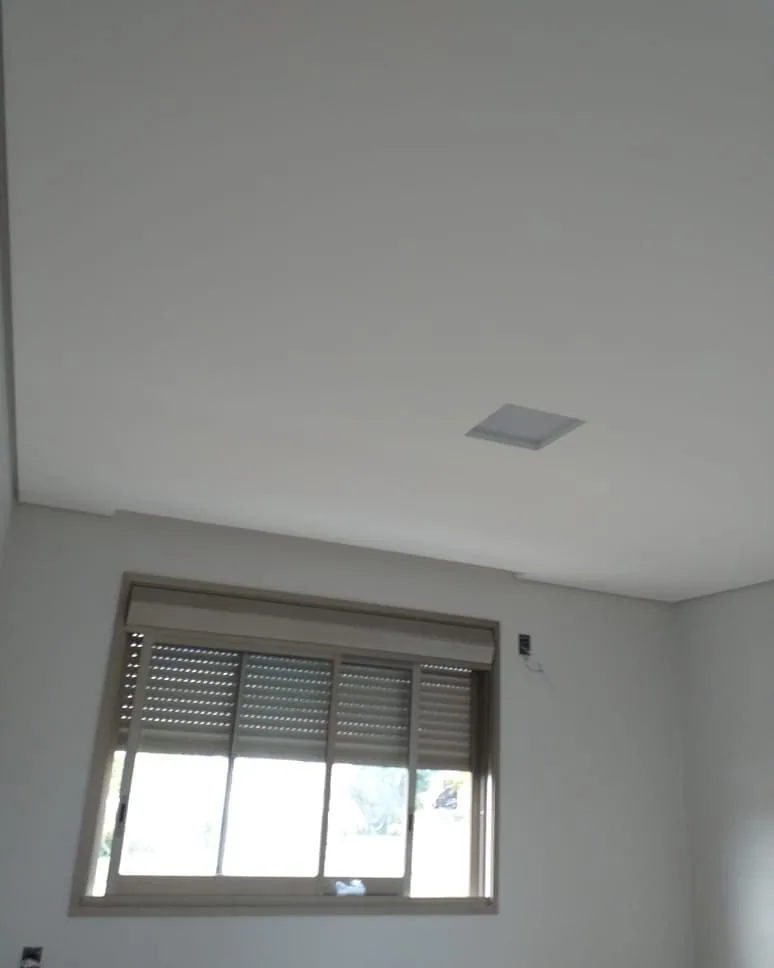 Casa na Península dos Pássaros, em Alphaville: quarto com janela de persiana e forro de gesso liso com alçapão quadrado