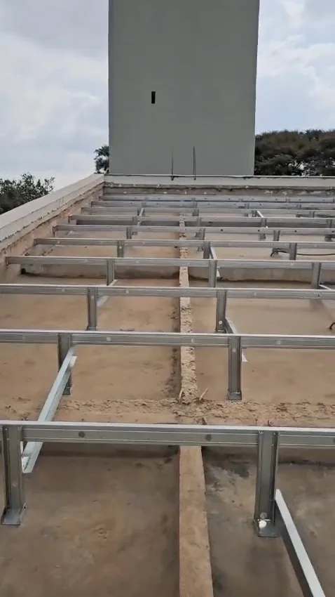 Quadro do vídeo: estrutura de perfis de aço galvanizado do telhado montada sobre a laje, com uma torre de concreto ao fundo
